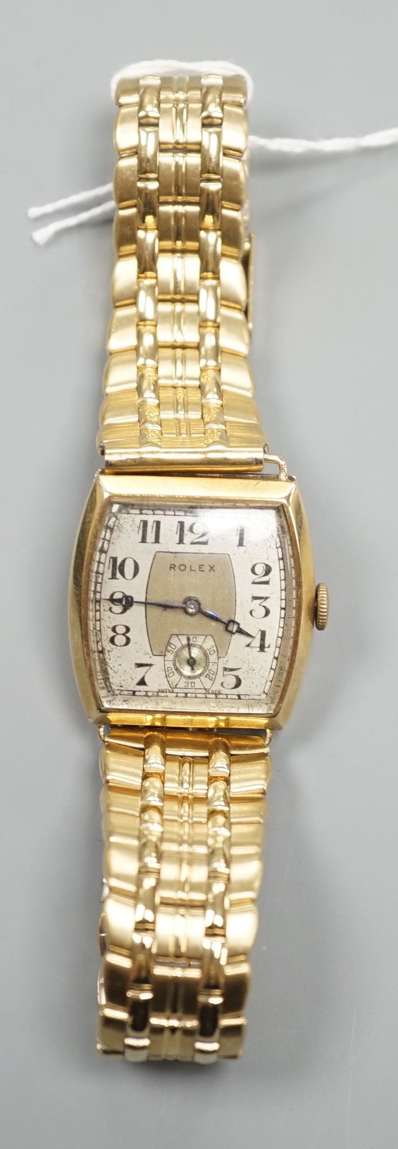 A gentleman's early 1930's 9ct gold Rolex manual wind wrist watch, with tonneau shaped case and Arabic dial with subsidiary seconds, on associated bracelet, case diameter 28mm.